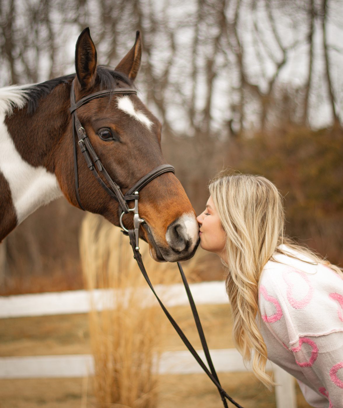 A rider giving her paint horse a kiss on the nose