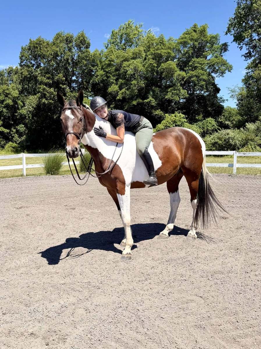 A rider leaning down to hug her horse in the arena