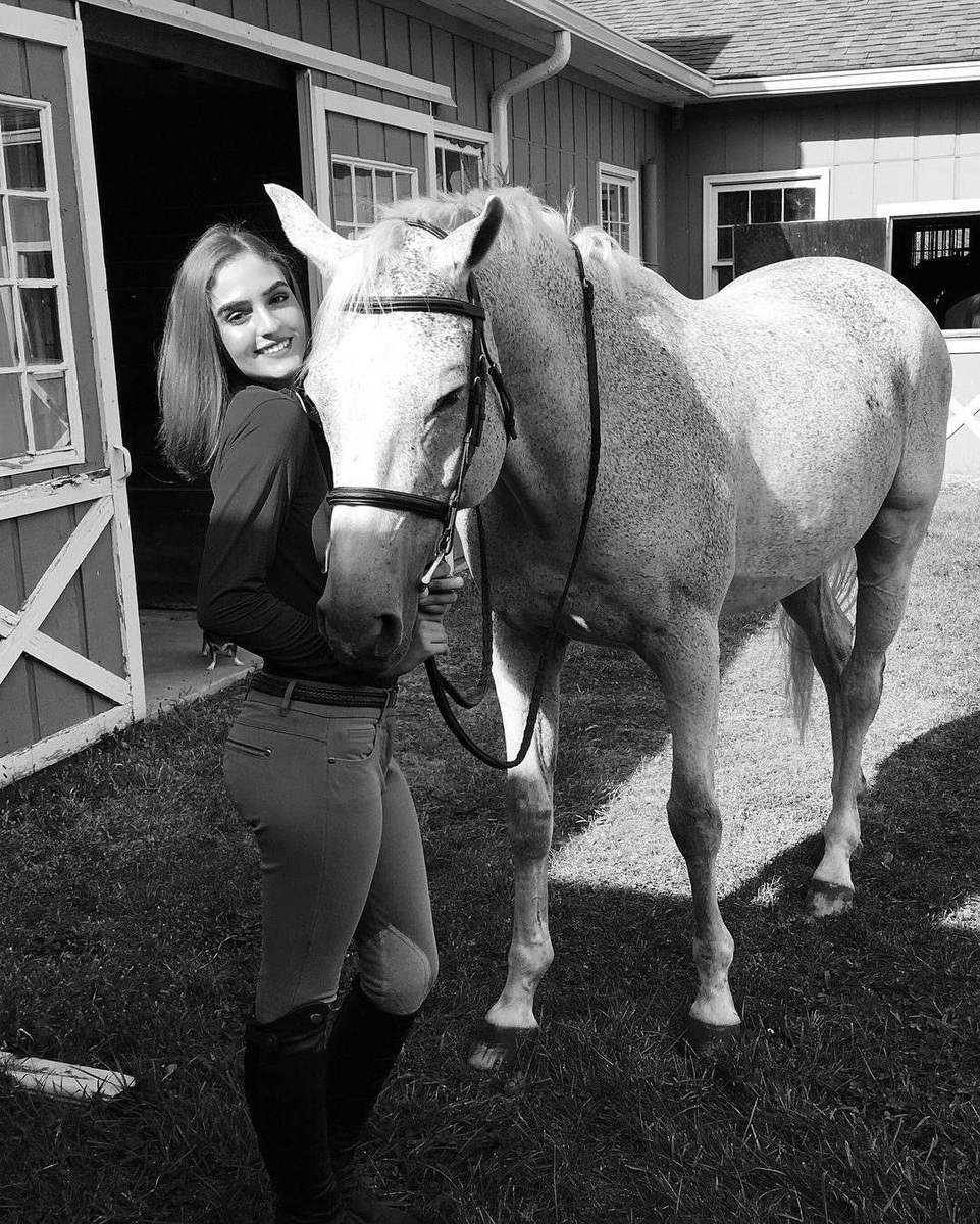 A rider with her grey horse at the barn
