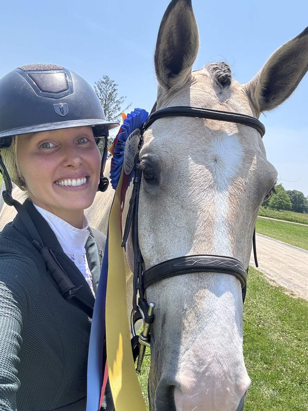A rider with her grey horse after a class