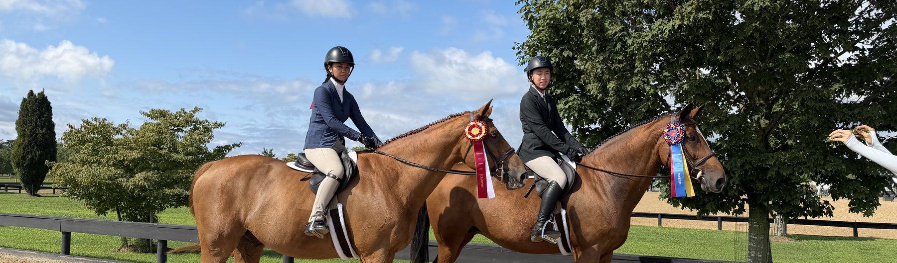 Two riders with their horses and championship ribbons after a show
